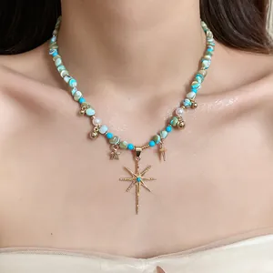 Close-up of Bohemian necklace with turquoise beads, pearls and star pendant on model.