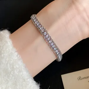 Detailed view of a sparkling silver twisted chain bracelet with cubic zirconia on a wrist.