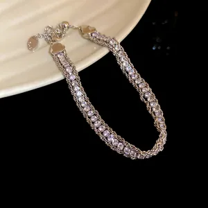 Close-up of a sparkling silver crystal multi-strand chain bracelet on a ceramic plate.