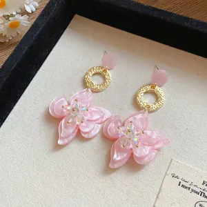 Detailed view of pink resin flower earrings with pearlescent petals and gold rings