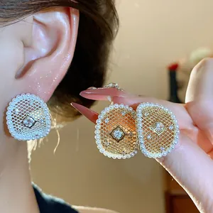 Dettaglio di orecchini a maglia placcati in oro 18k con perle e zircone al centro