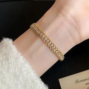 Close-up of a gold-plated twisted chain bracelet with shimmering inlaid crystals