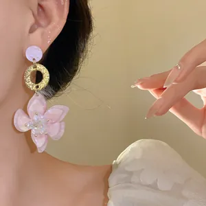 Close-up of elegant pink resin flower drop earrings with gold textured ring on model ear