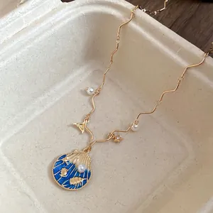 Close-up of golden bohemian shell pendant necklace with blue enamel and pearls