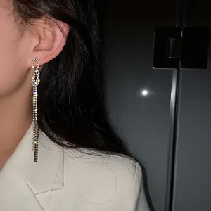 Detailed shot of sparkling rhinestone bow tassel earrings worn by a model