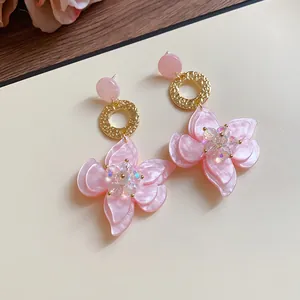 Detail view of pink resin flower drop earrings with shimmering crystal centers