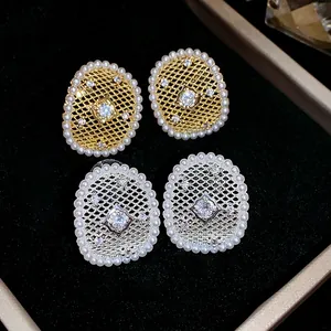 Dettaglio macro di orecchini a perno ovali placcati oro e argento con perle e zircone