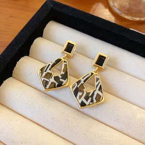 Detail shot of geometric hollow earrings with black rectangular gems in gold frames