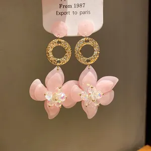 Detailed view of elegant pink resin flower drop earrings with golden textured rings
