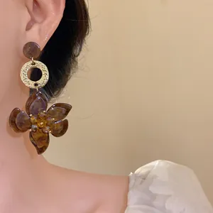 Detailed close-up view of brown resin flower earrings with gold hammered ring accent