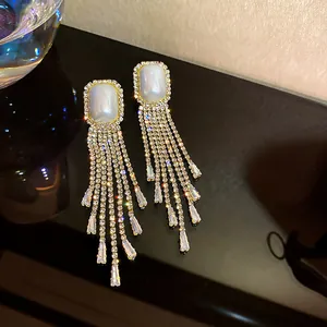Detailed view of glamorous long rhinestone fringe earrings with white rectangular stone