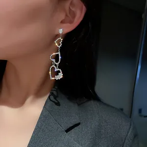 Sparkling crystal-encrusted tiered heart drop earrings presented on a model's ear