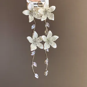 Primo piano di orecchini a fiore con petali bianchi e pietre di zircone