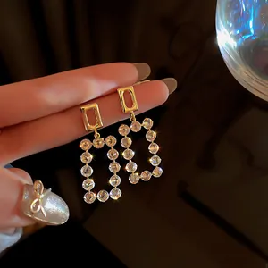 Macro view of elegant gold-toned rectangular drop earrings with sparkling clear crystals