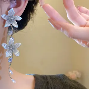 Dettaglio degli eleganti orecchini a nappa con fiori bianchi, zirconi e argento