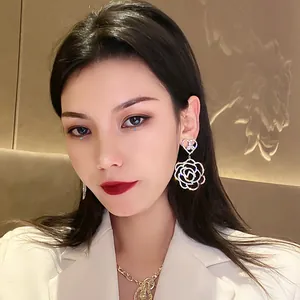 Detailed close-up of a model wearing sparkling crystal hollow rose statement earrings