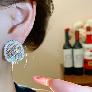 Primo piano di eleganti orecchini a lobo placcati oro 18k con perle e zircone