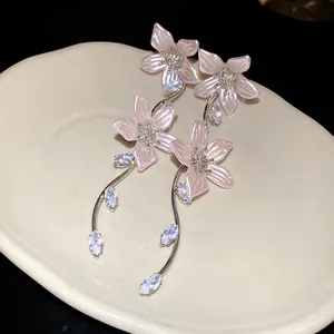 Primo piano di eleganti orecchini a fiore rosa con pendenti e accenti in zircone lucido