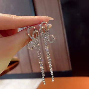 Detailed view of sparkling rhinestone bow tassel drop earrings with silver needle