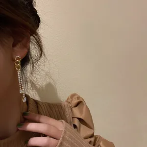 Elegant gold chain-link earrings with long sparkling rhinestone tassels on a model