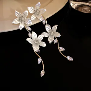 Eleganti orecchini a nappa con fiori d'argento e dettagli in zircone su fondo scuro.