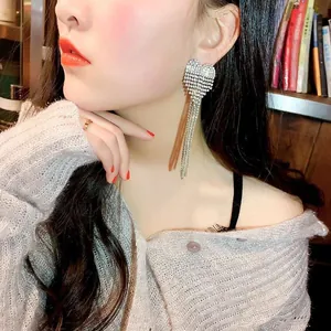 Detailed view of silver heart-shaped tassel earrings with sparkling rhinestones.
