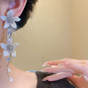 Dettaglio di eleganti orecchini a nappa con fiori bianchi e pietre di zircone