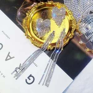 Close-up detail of oversized heart rhinestone tassel earrings with sparkling crystals
