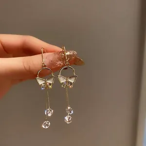 Detail of gold butterfly drop earrings with shimmering crystals and long tassels