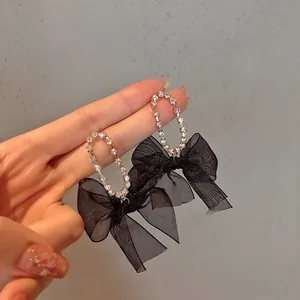 Detailed macro shot of elegant black mesh bow earrings with glistening rhinestone accents