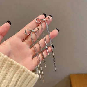 Close-up of elegant silver bow tassel earrings held in hand to show size and sparkle