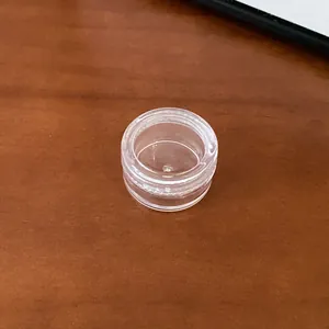 Close-up view of a small transparent round plastic storage container for jewelry
