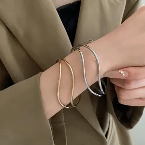 Braccialetti rigidi minimalisti in metallo ondulato oro e argento indossati sul polso