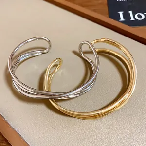 Dettaglio di bracciali a fascia multistrato minimalisti in argento e oro lucido
