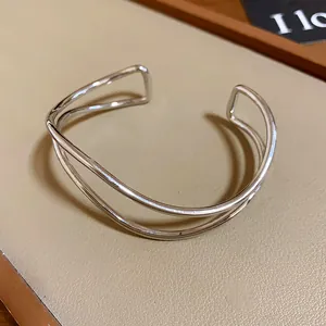 Dettaglio di un bracciale rigido aperto multistrato minimalista in metallo argento.
