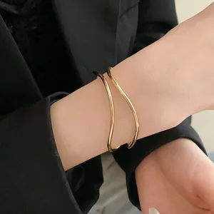 Vista dettagliata di un elegante bracciale rigido dorato ondulato su un polso