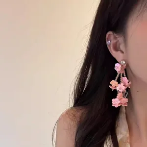 Detailansicht eleganter rosa Pailletten-Blumen-Quastenohrringe an einem asiatischen Modell