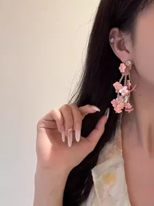 Detailansicht: Model trägt rosa Pailletten-Blumenohrringe mit Quasten und Zirkon.