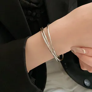 Dettaglio di un bracciale rigido aperto a più strati incrociati in stile minimalista