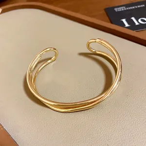 Dettaglio di un bracciale rigido aperto multistrato dorato minimalista da donna