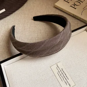 Gros plan sur un serre-tête en tissu rayé marron avec détails de tissage élégants.