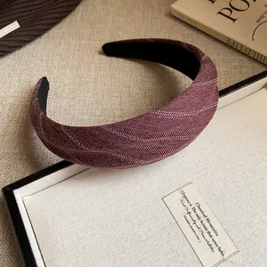 Gros plan d'un serre-tête en tissu rayé bordeaux avec motif à chevrons.