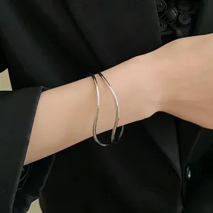 Primo piano di un bracciale rigido ondulato argento multistrato minimalista su modella
