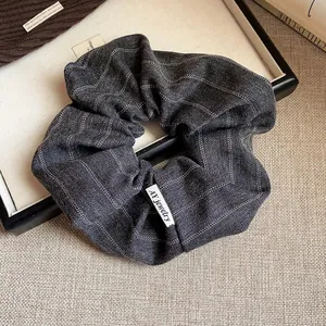 Gros plan d'un chouchou élégant en tissu à rayures grises avec une texture d'automne