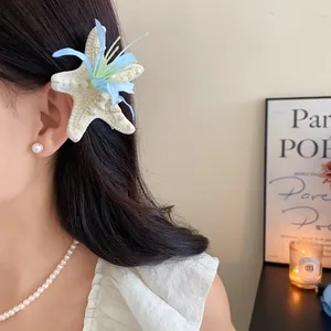 Close-up detail of a starfish and blue flower hair clip worn by a model for beach vacation