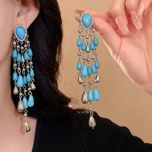 Close-up view of long ethnic style turquoise teardrop tassel earrings with silver accents