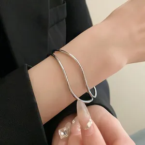 Dettaglio di un bracciale rigido aperto a più strati color argento dal design minimalista