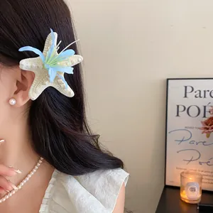 Detailed macro shot of a white starfish and blue flower hair clip on a model's hair