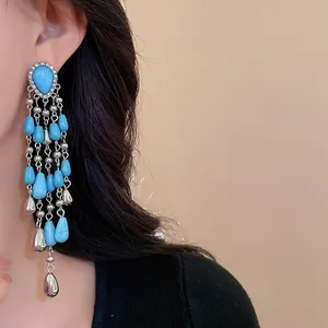 Close-up detail of Bohemian style long turquoise tassel earrings worn by a model