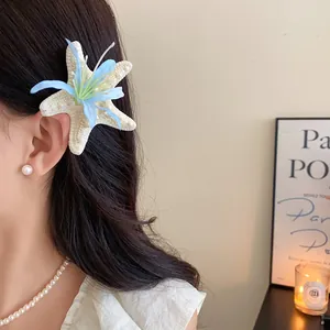 Close-up detail of a starfish hair clip with a blue flower worn on elegant dark hair
